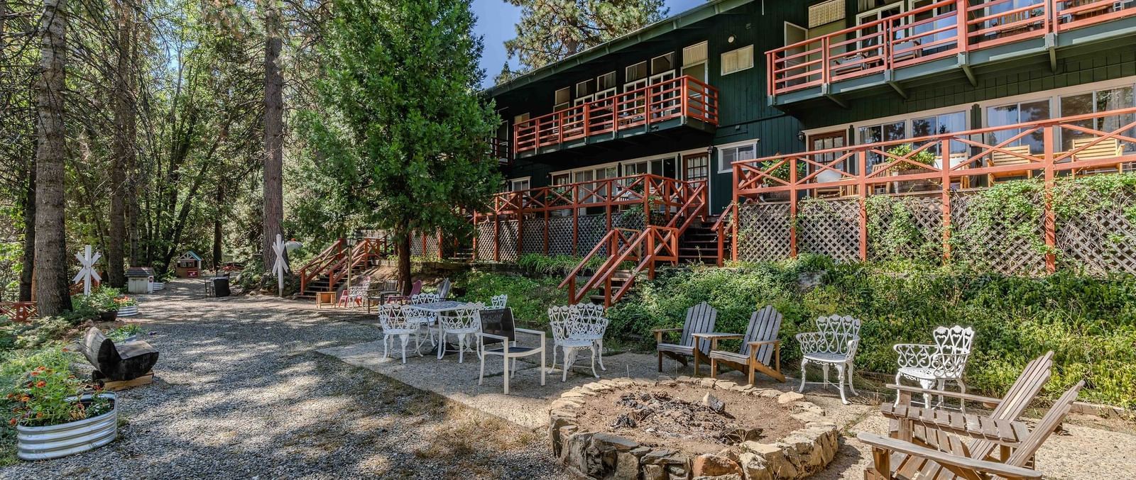 Exterior of Narrow Gauge Inn, with a spacious walkway, trees surrounding the Inn, and chairs placed in the lawn area.