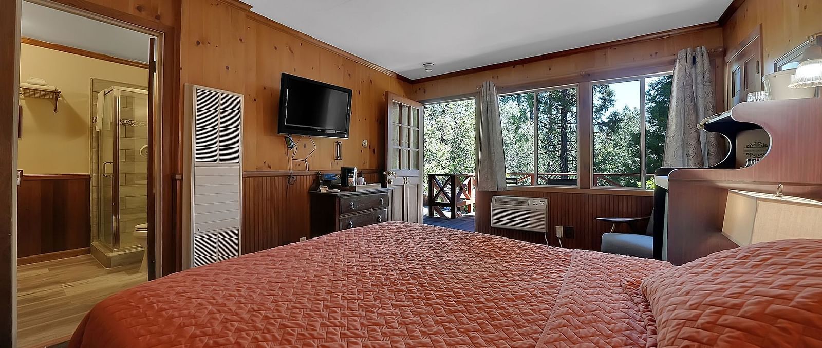 A view of a room at Narrow Gauge Inn with a double bed and sliding doors opening to a balcony.