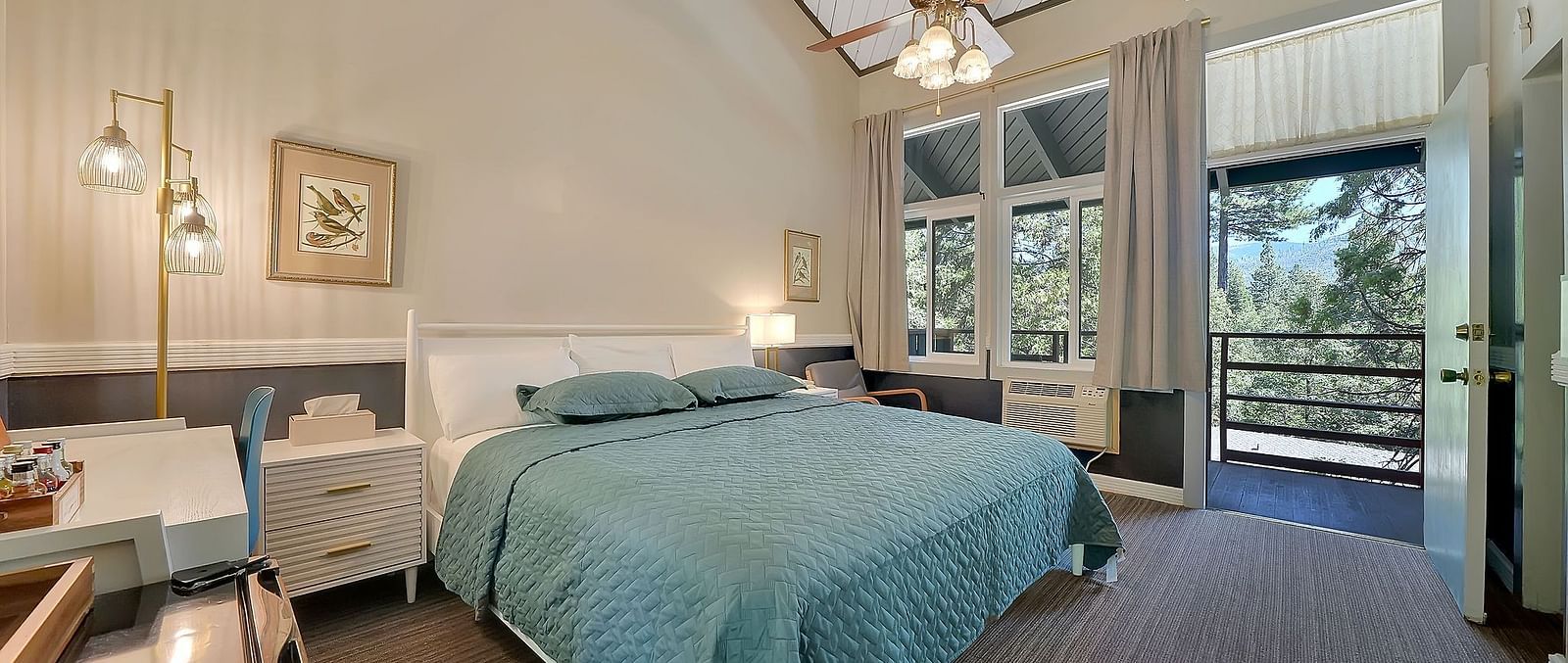 A view of a room at Narrow Gauge Inn with a double bed and sliding doors opening to a balcony.
