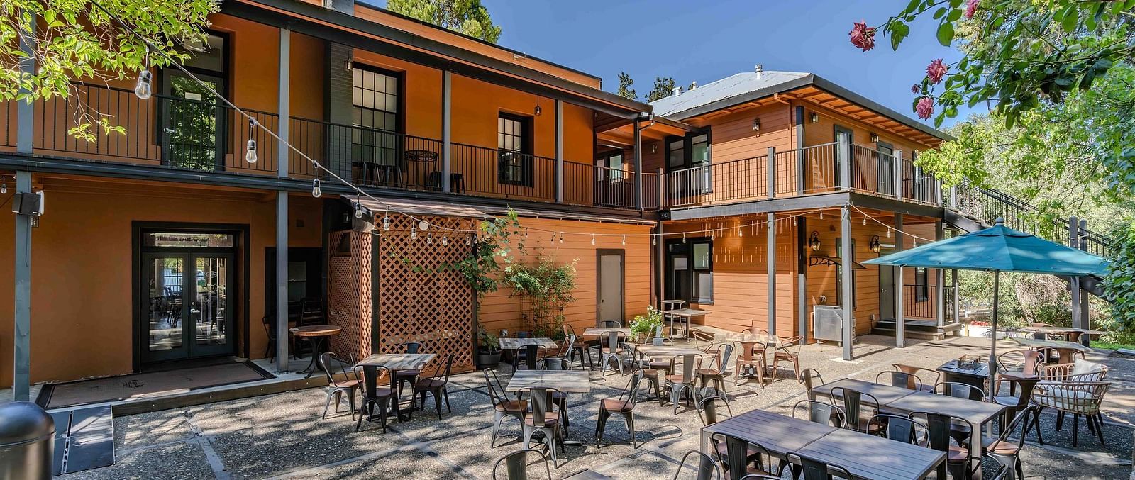 Exterior of The Groveland Hotel with a backyard with outdoor dining.