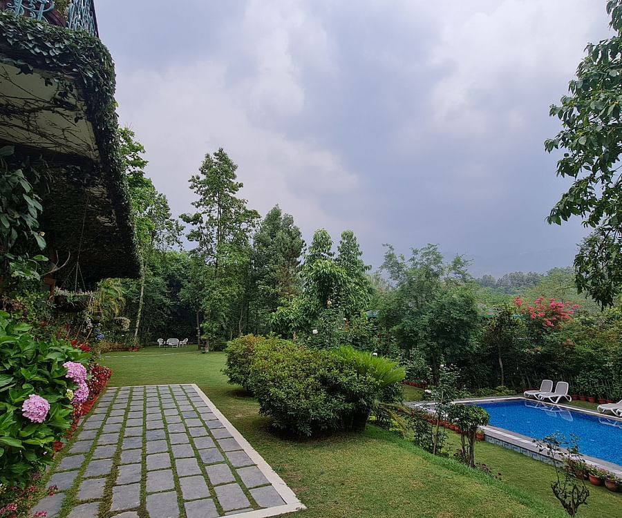 A view of a swimming pool and garden with a mountain backdrop.