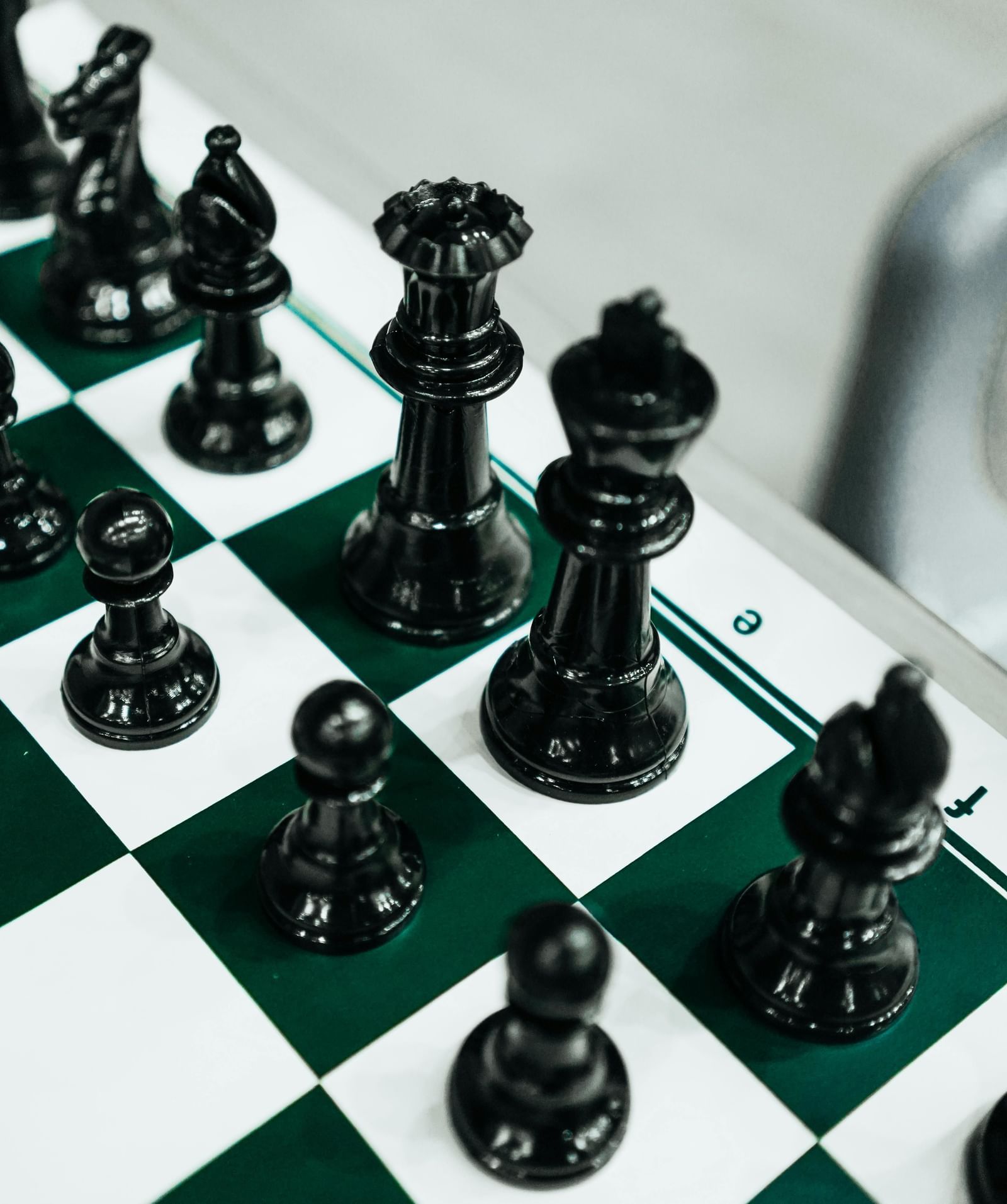 Close-up of a chessboard with neatly arranged black pieces.
