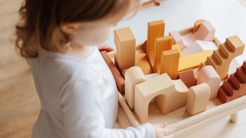a small girl playing with wooden blocks on a table