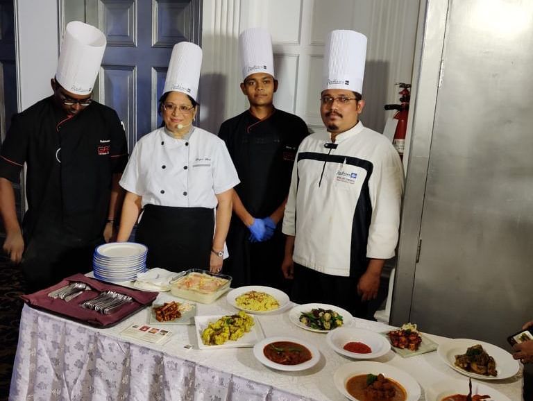 Chefs showcasing prepared dishes at a culinary event.