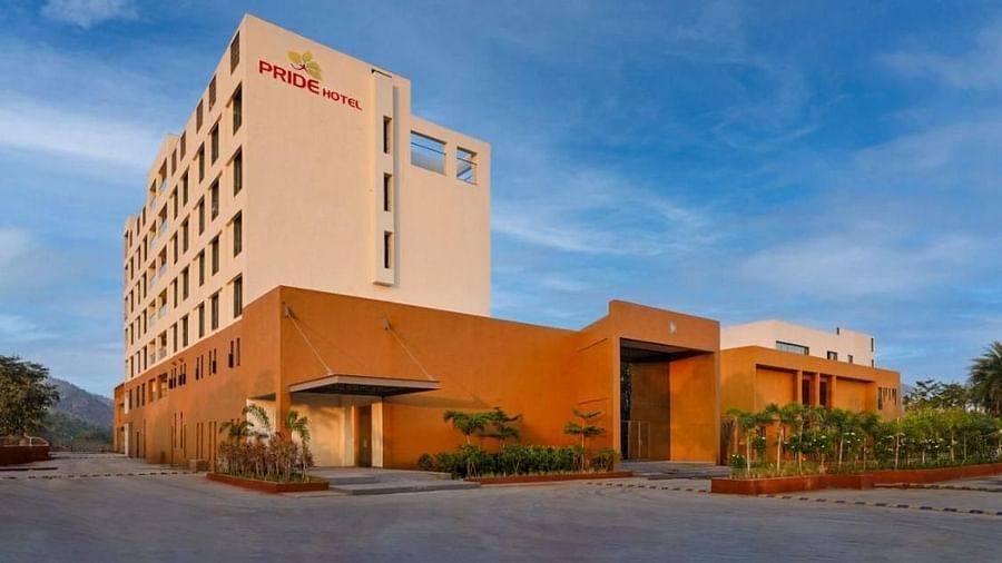 A beautiful shot a Pride Resort Ambaji's building surrounded by plants with the beautiful blue sky in the background