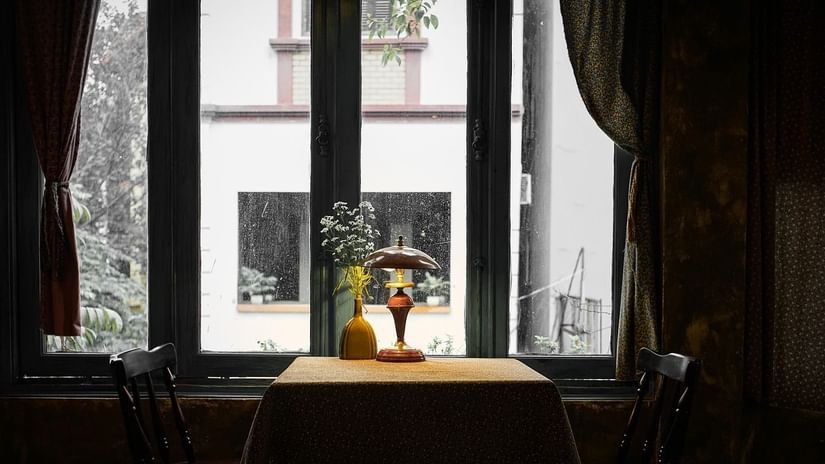 An inviting indoor space with a table by a large window, offering a view of greenery outside.