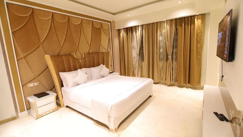 The lush white bed with an artistic background and a TV mounted on the wall in front of it