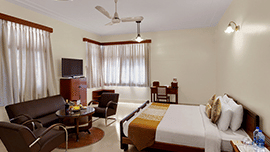 A Superior Room at Trance Sunderban Resort with a double bed, a leather sofa, and a coffee table set in a large living area.
