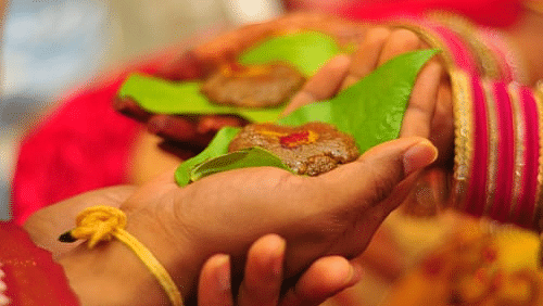 groom and bride holding beetle leaves for wedding rituals