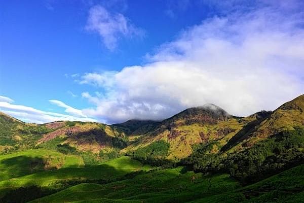 Rolling hills under a bright sky with scattered clouds.