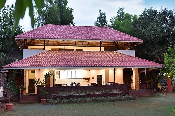 A facade view of the restaurant at Riverside Inn, with lights glowing from inside and trees in the background.