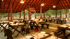 Open hall restaurant in Abad Turtle Beach Resort, the best resort in Alleppey, featuring dining tables and benches prepared to serve guests