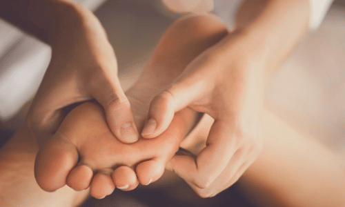 Hands pressing on a person’s foot during a massage session
