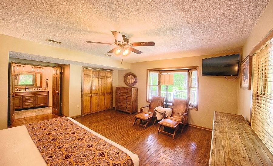 corner view of a beautiful room with a double bed and reclining arm chairs with ceiling fan in the middle of the room - Historic Tapoco Lodge