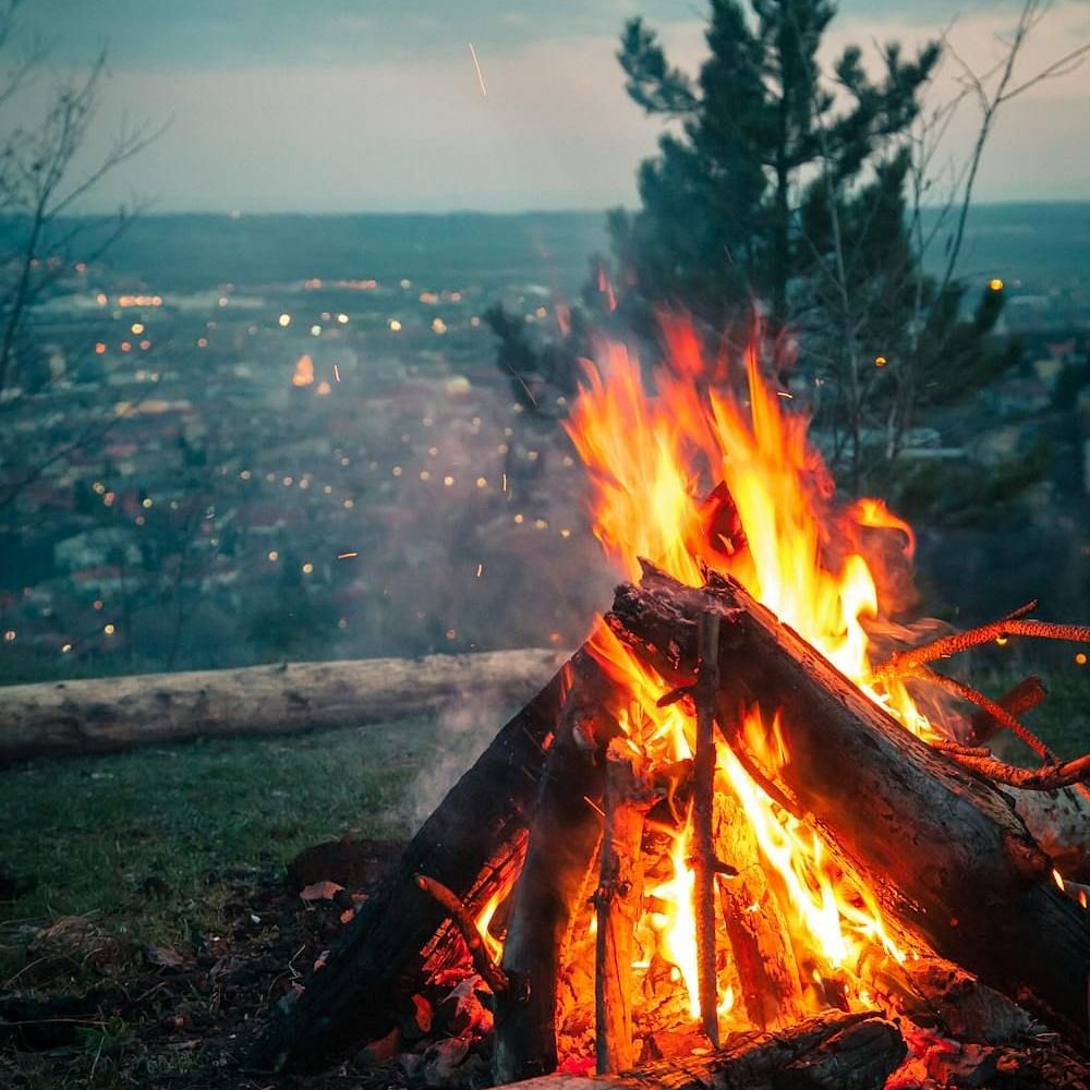 Image of bonfire with a city view in the background.