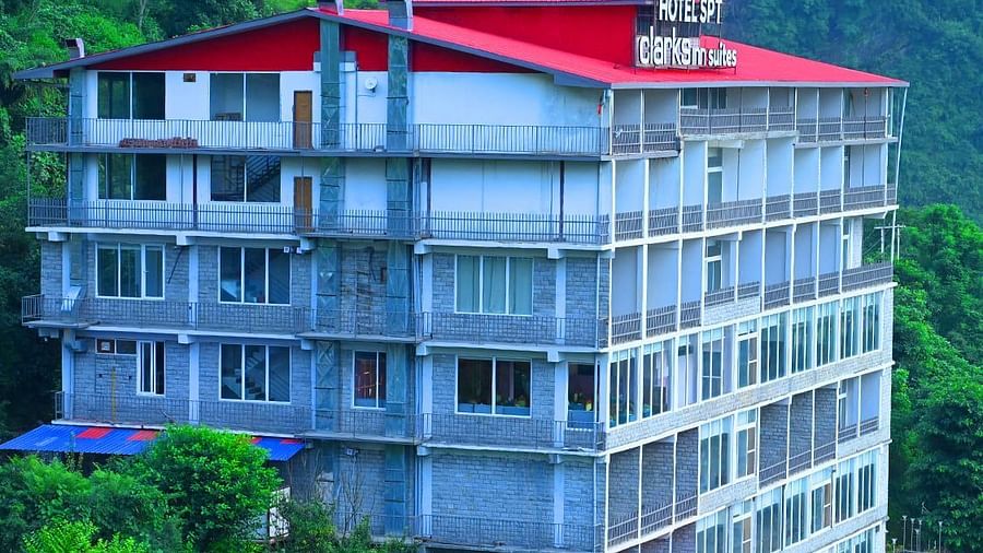 Facade of SPT Clarks Inn Suites, Mandi amidst lush greenery with a glimpse of a mountain in the bakcground