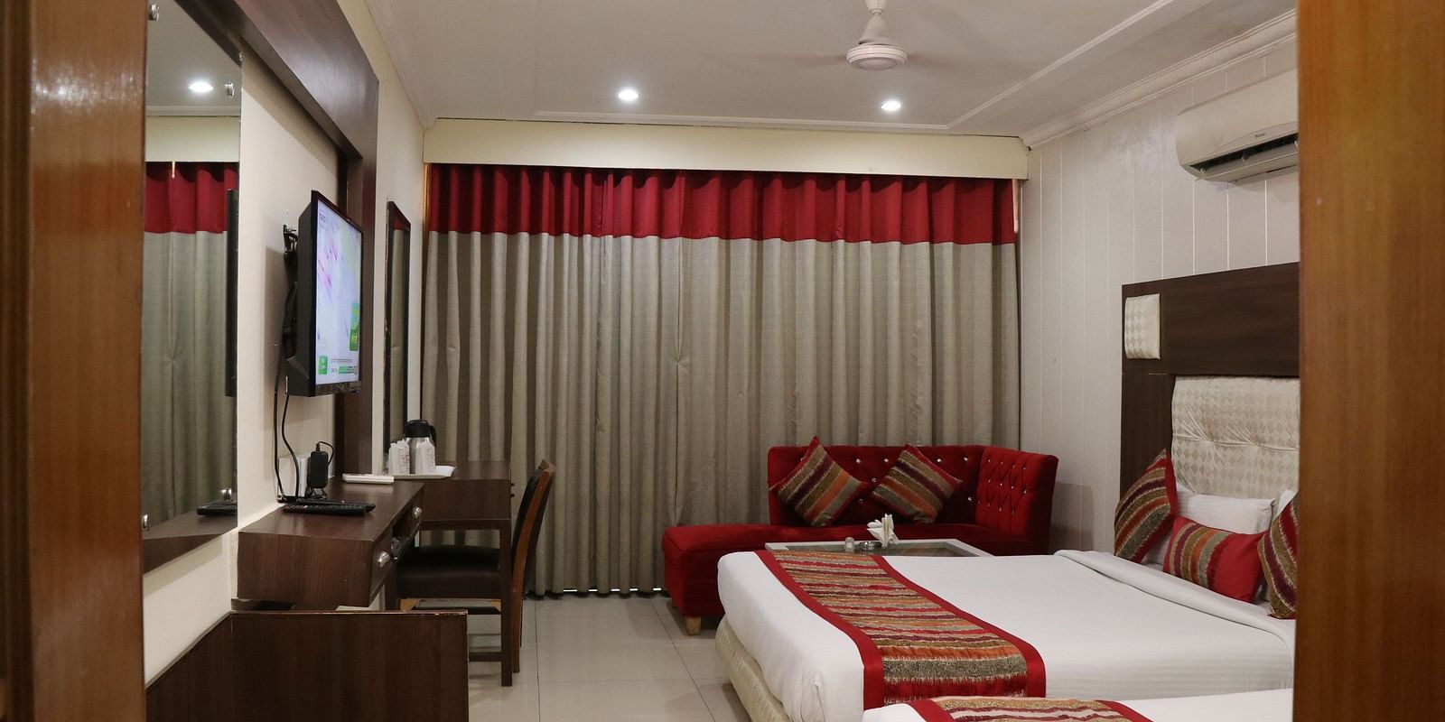 Modern hotel room with two queen size beds, a wall-mounted TV, and a cosy ambience - Hotel Diamond Plaza, Chandigarh.