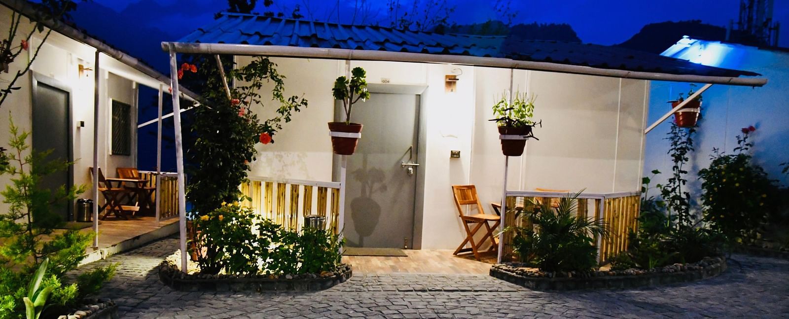 facade image of the deluxe room exterior during the night with stone pathway in front of it - The Tattva Boutique Resort