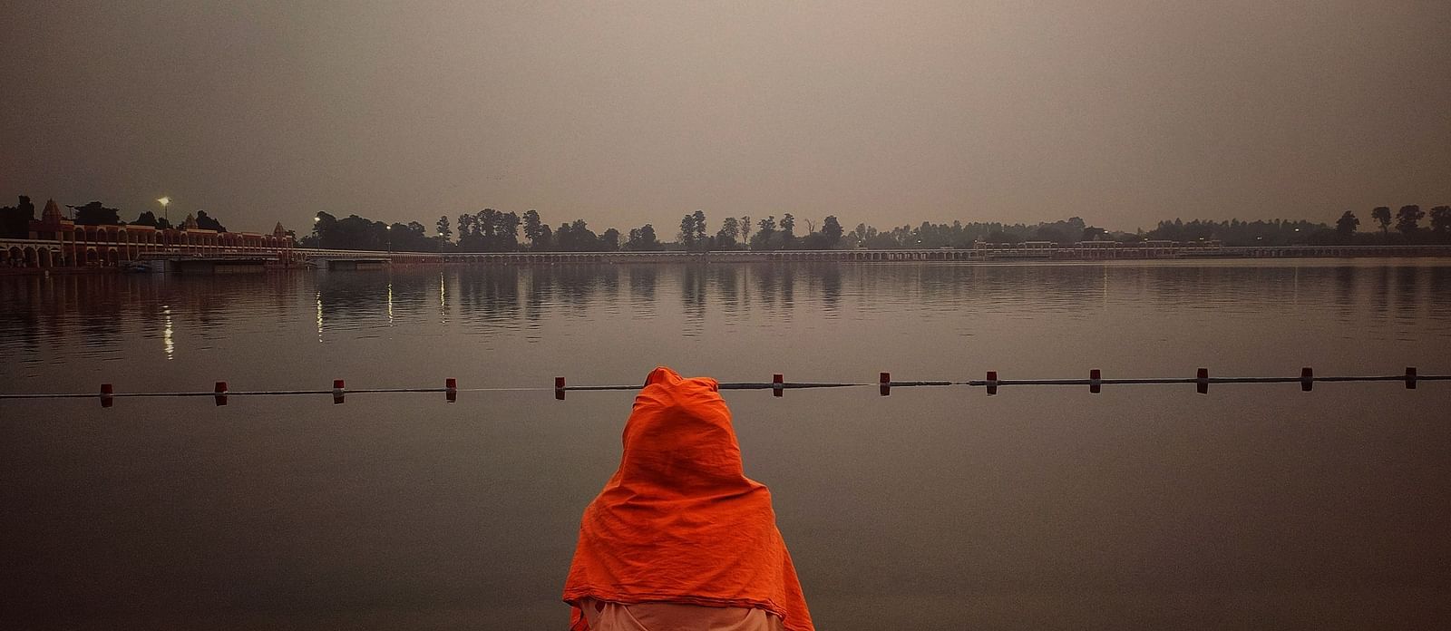 an image of a man sitting on the shore of a lake