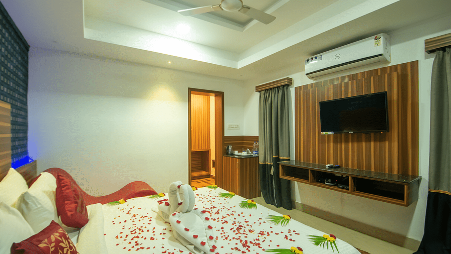 A room with a bed decrated with flower petals and leaves at Parampara Resort & Spa, Kushalnagar.