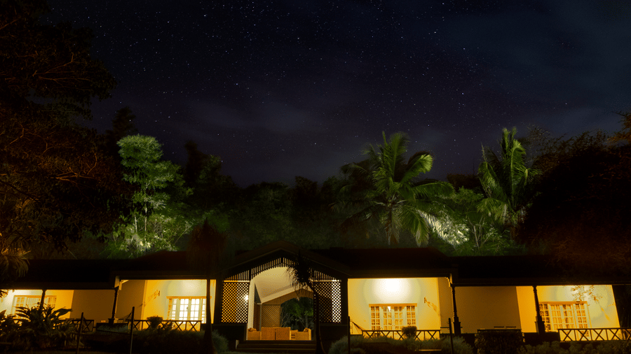 The Waterfront Verandah at The Serai Kabini is illuminated at night, with the verandah opening towards the surrounding landscape and trees.