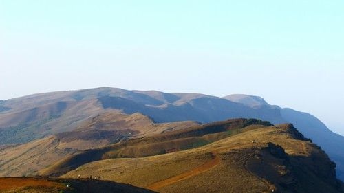 a view from Mullayanagiri Peak of the rolling mountains with blue sky in the background
