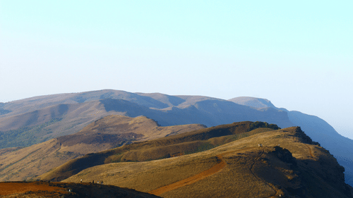 a view from Mullayanagiri Peak of the rolling mountains with blue sky in the background