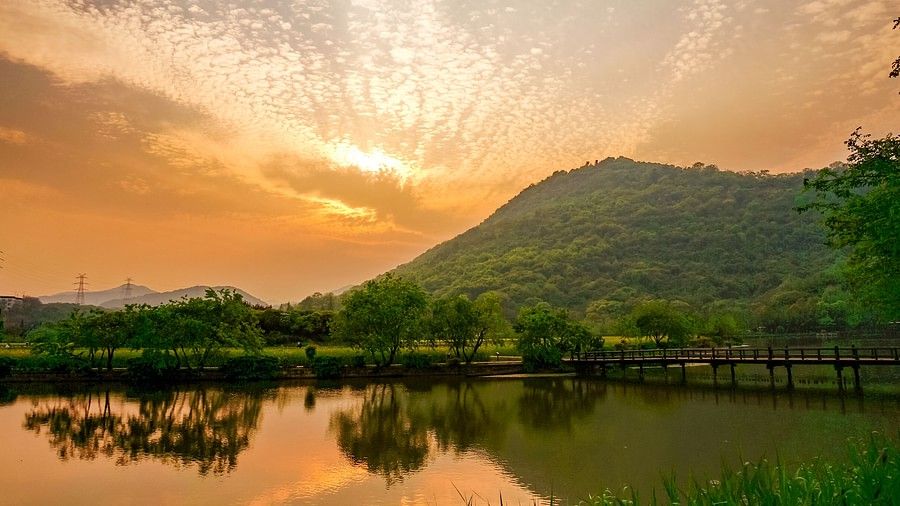 A tranquil landscape of a calm lake reflecting a dramatic sky over hills.