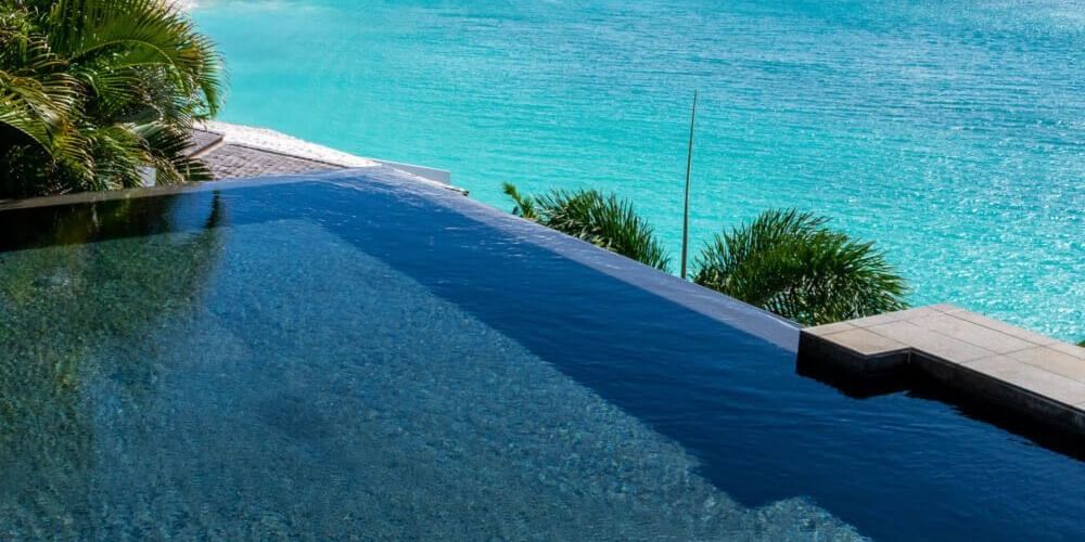 Infinity pool overlooking the ocean with tropical trees and blue skies at Tamarind Hills Resort and Villas - Antigua.