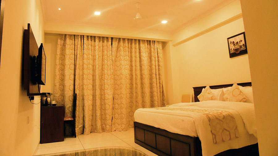 A side view of a bedroom shows the off-white interiors and the TV on the wall - VITS ExcellenSea, Dapoli