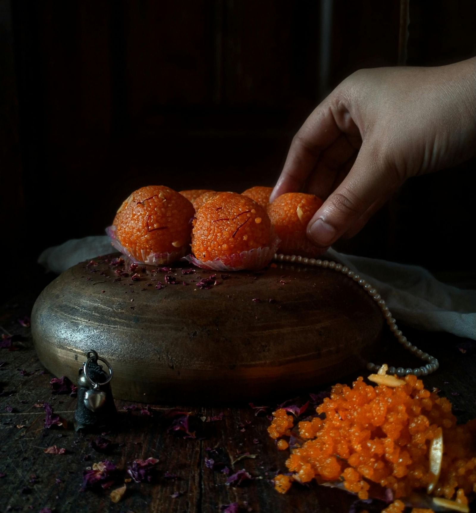 A person picking a ladoo from a bunch of a ladoo's with his hand.