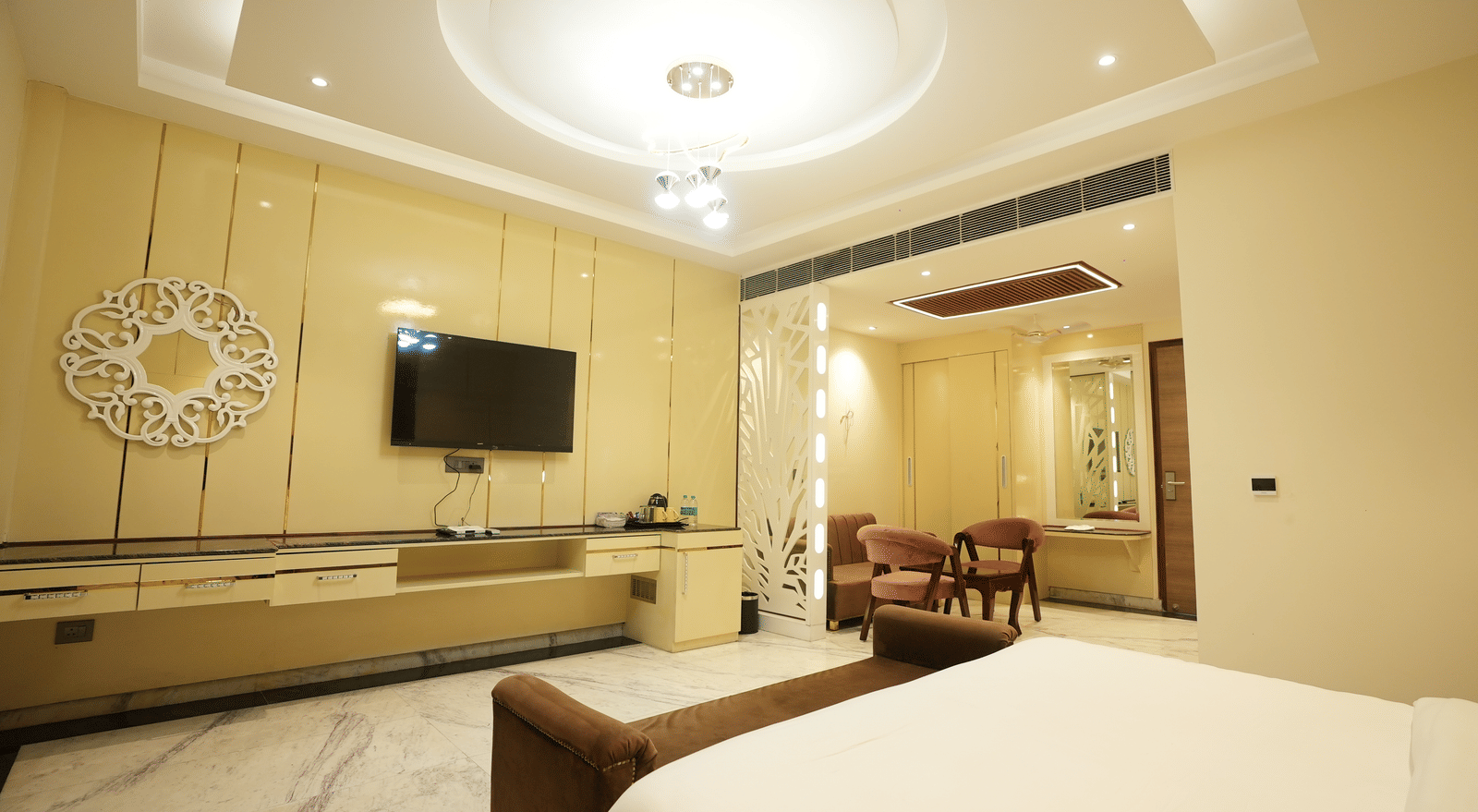 A bedroom, featuring a bed, a flat TV screen, and a seating area with table and chairs at Lime Tree Hotel Near India Expo Mart, Greater Noida.
