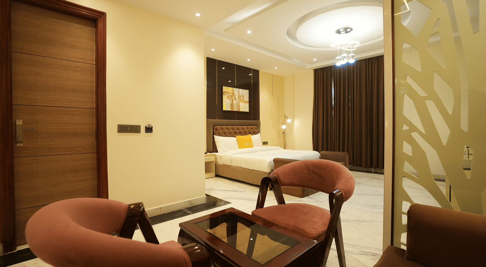 Cosy seating area at Lime Tree Hotel Near India Expo Mart, Greater Noida with king size bed, ceiling-floor windows, and warm lighting.