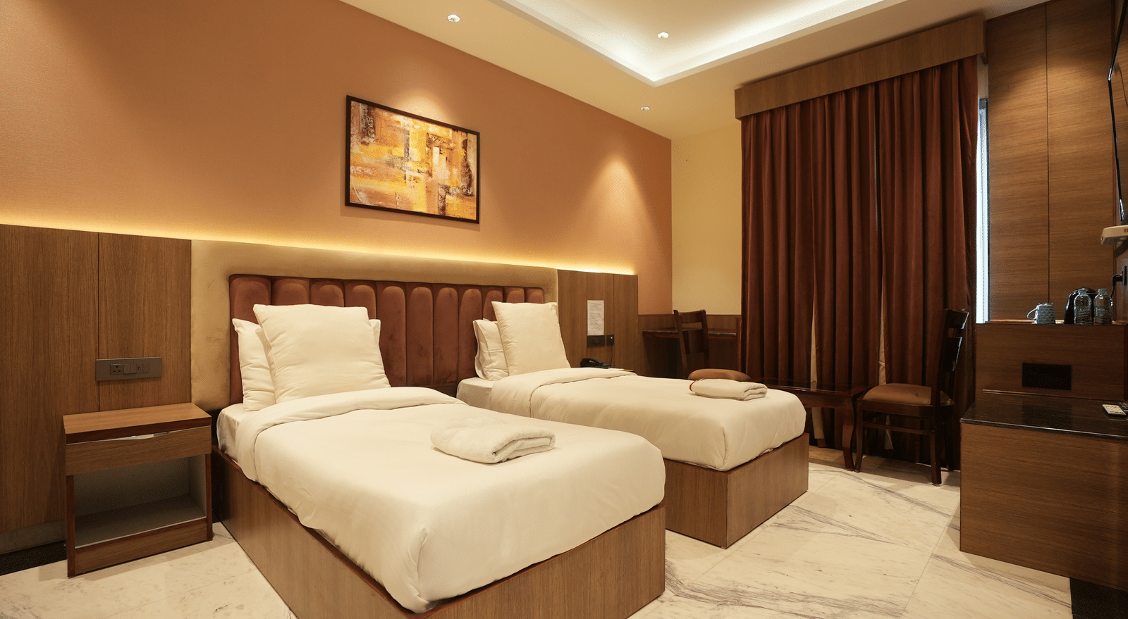 Twin bed room with wall art and warm lighting at Lime Tree Hotel Near India Expo Mart, Greater Noida.