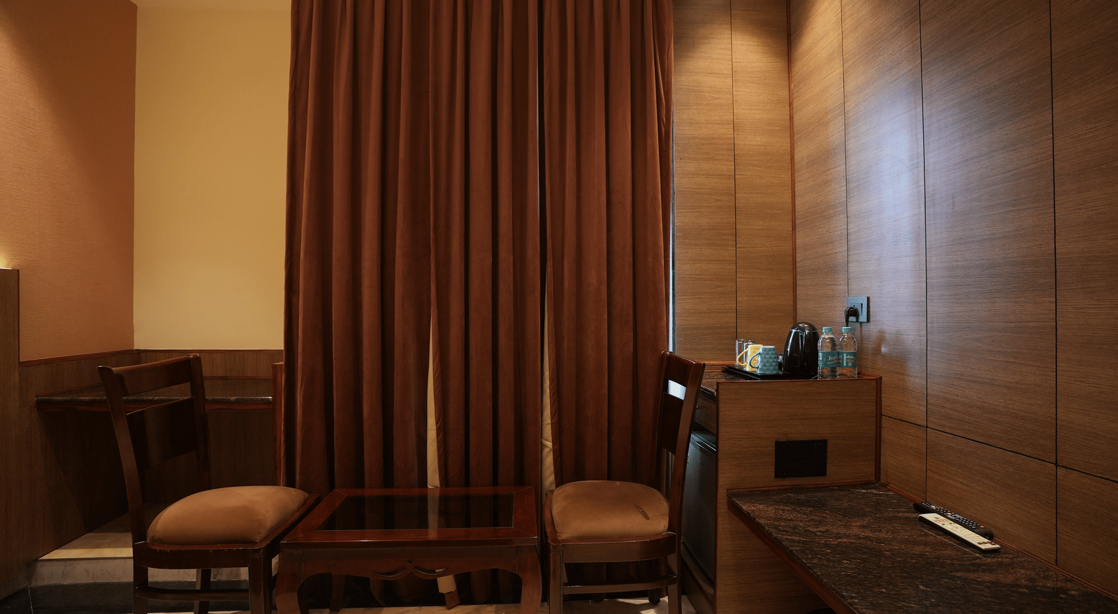 Work desk and chair setup with brown curtains at Lime Tree Hotel Near India Expo Mart, Greater Noida.