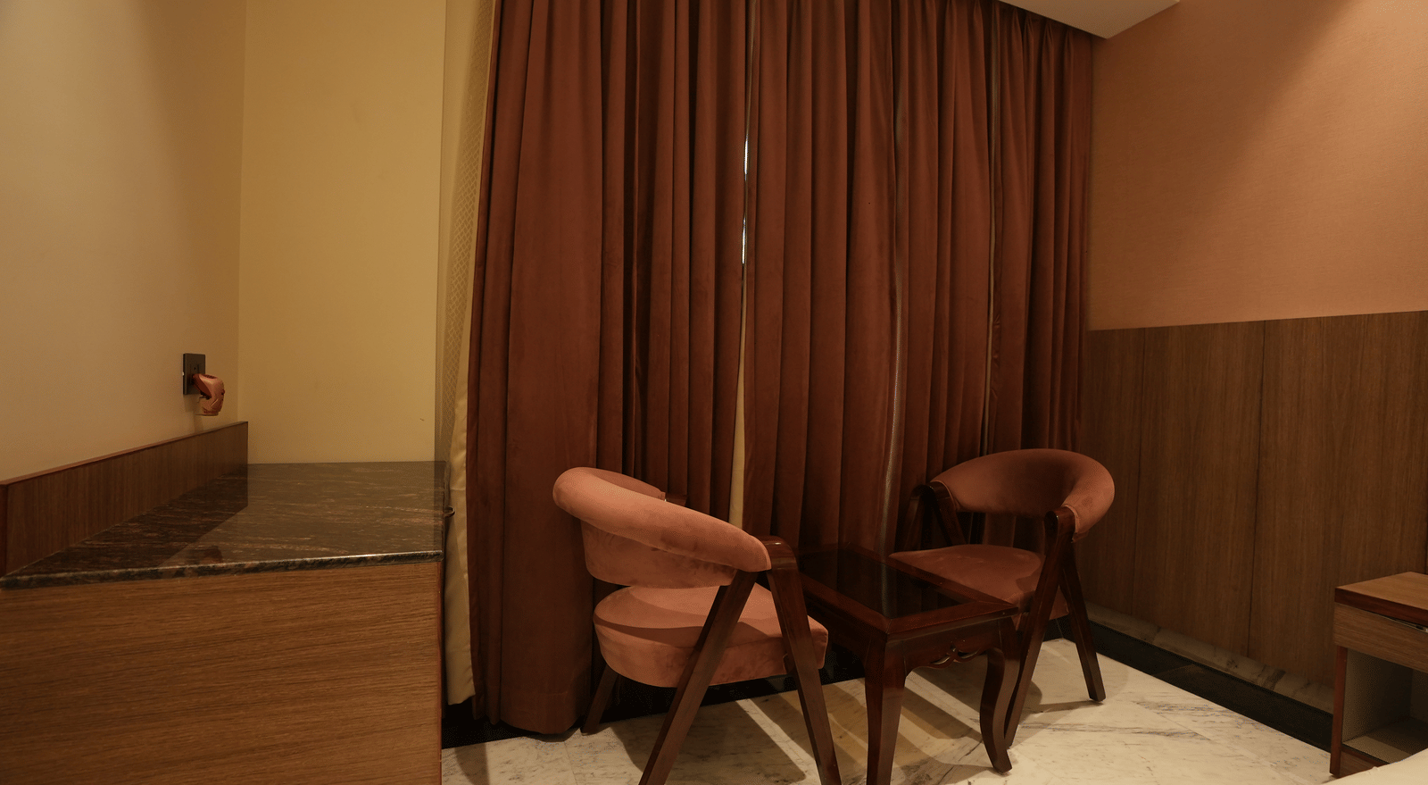 Cosy seating space with two chairs and a table at Lime Tree Hotel Near India Expo Mart, Greater Noida.