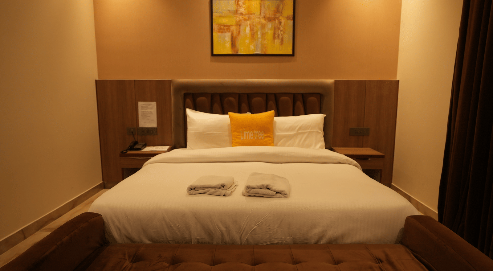 Room with king size bed, pillows, and soft lighting at Lime Tree Hotel Near India Expo Mart, Greater Noida.