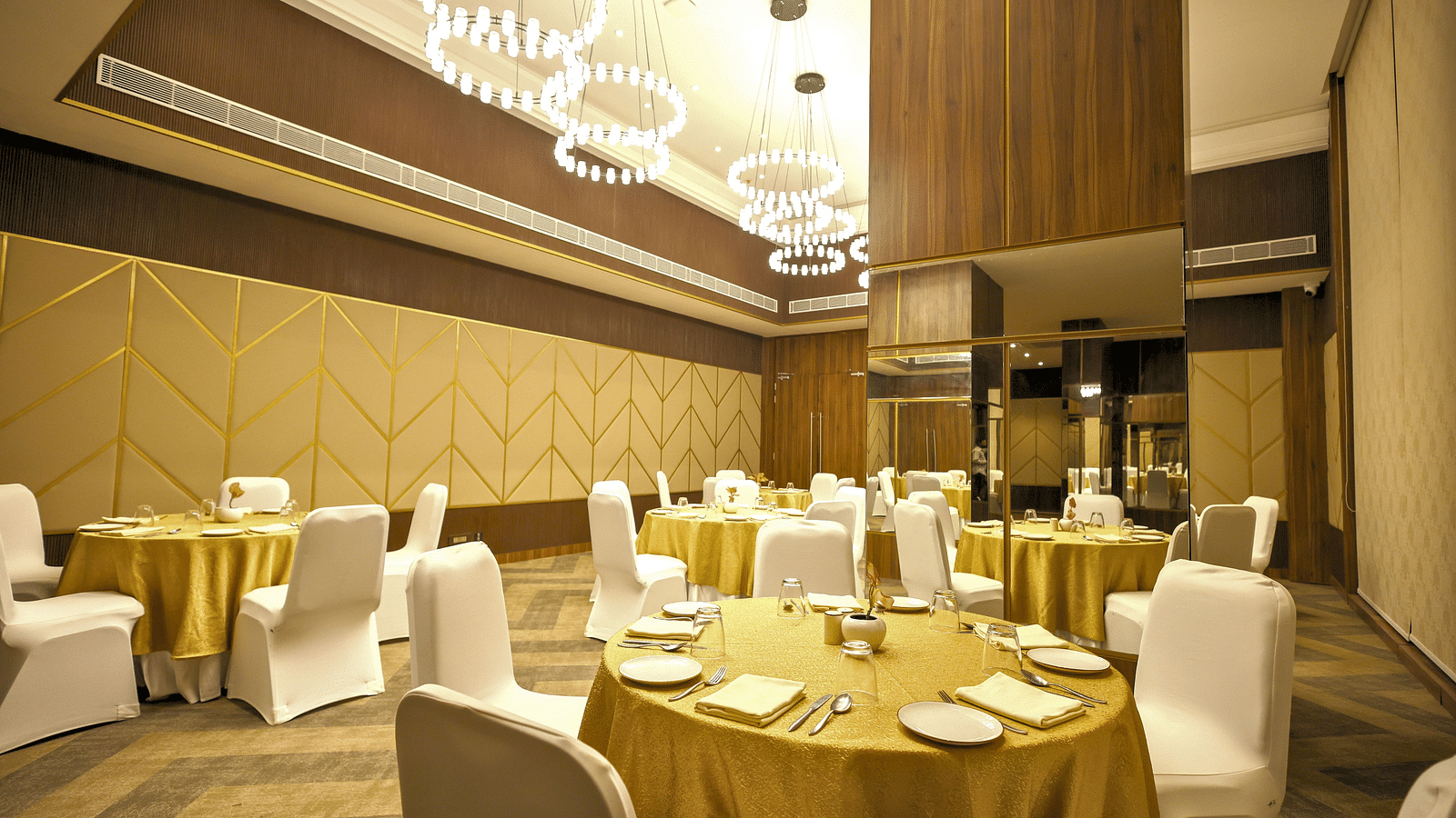 A banquet hall set up with round tables draped in brown linens and white chair covers, ready for a special event at Rhythm Gurugram Hotel and Suites. 