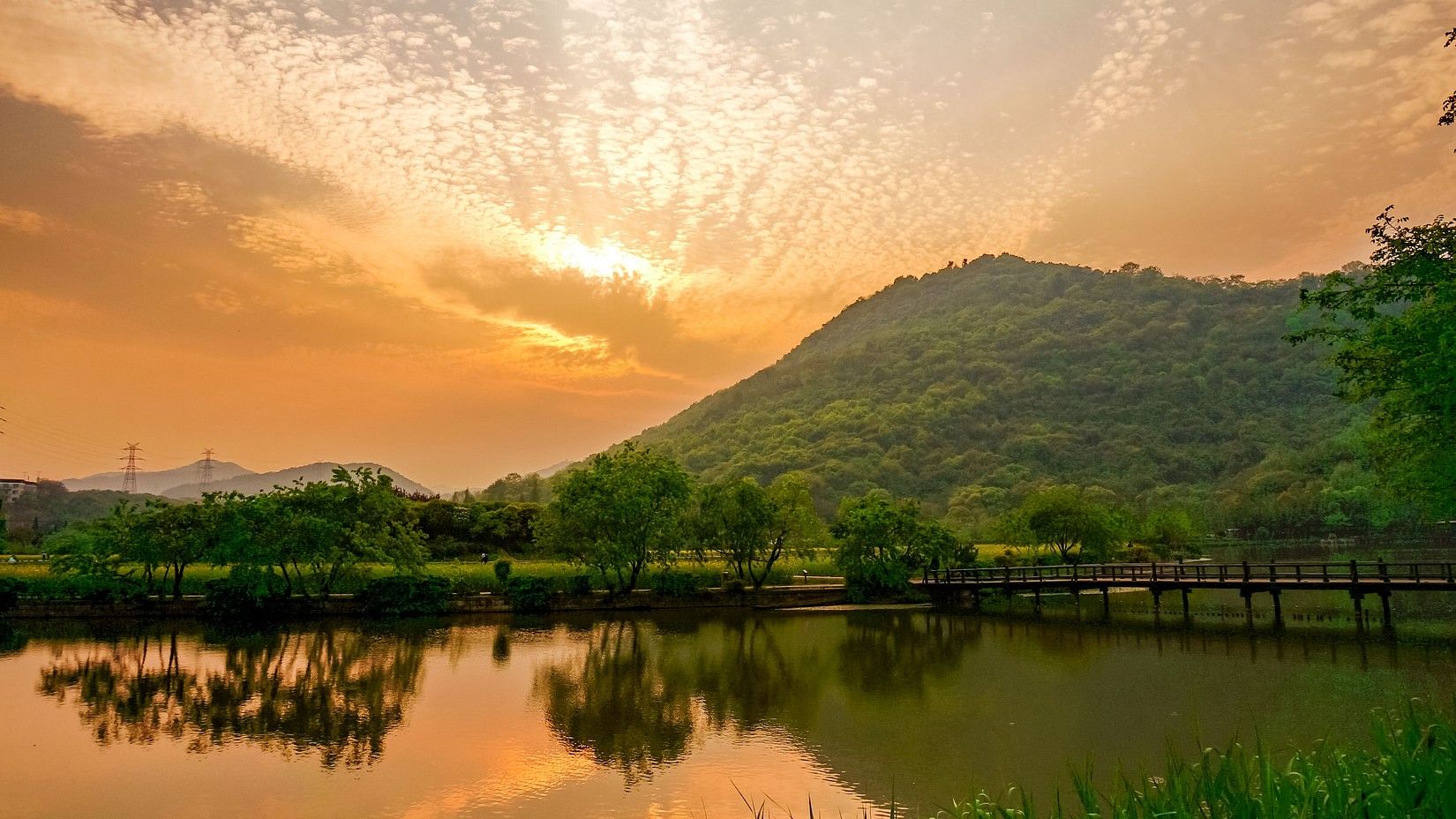 A tranquil landscape of a calm lake reflecting a dramatic sky over hills.