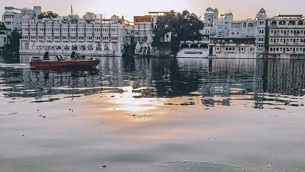 City buildings reflected in still water under a pale sky.