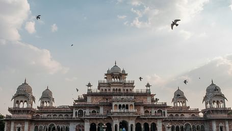 Exterior of a palace during a cloudy day with birds flying over it