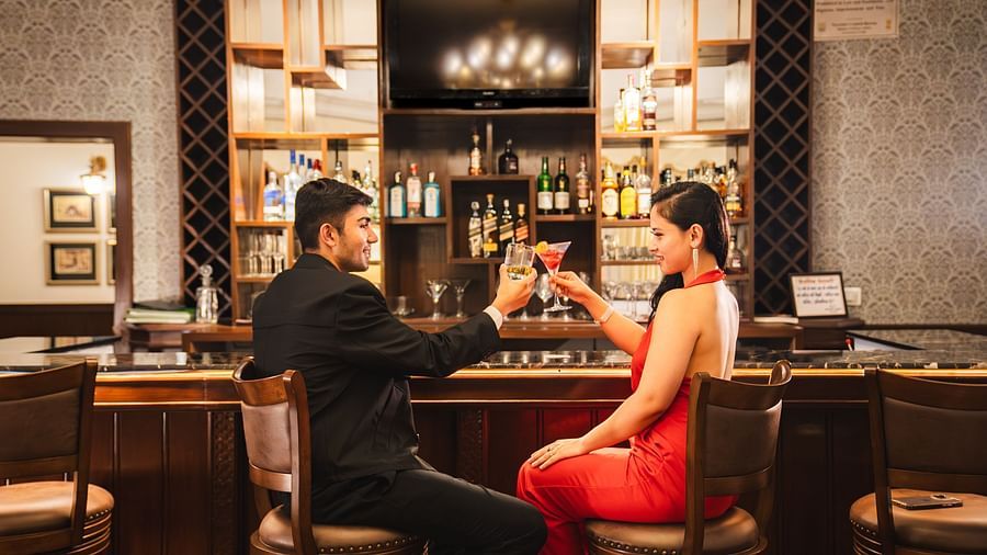 Couple toasting cocktails in a cozy, stylish setting at The Claridges Nabha Residence
