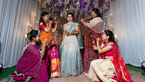 Five four in a Sangeet ceremony posing around the bride who is ready to dance on a stage.