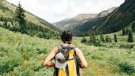 A woman backpacker standing in a lush green valley