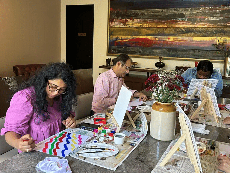 Guests gathered around a table indoors, engaged in arts and crafts at Karma Chalets.