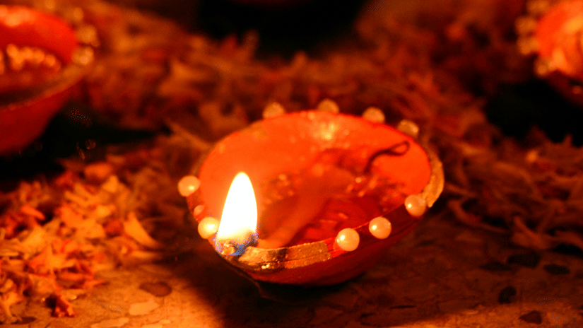 A row of diyas or traditional lamps surrounded by flowers