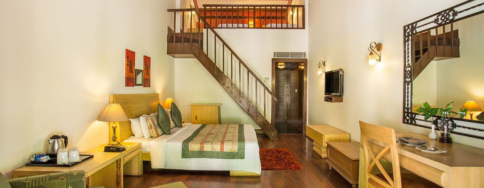 An image of a room with internal stairs leading to the attic, a king size bed, seating area  with chair, tables, and sofa - The Riverview Retreat, Corbett
