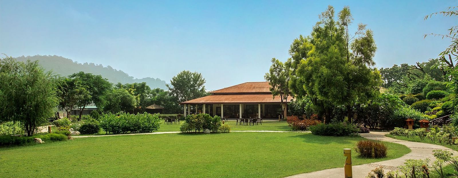 An image of a huge lawn with trees and in one corner there is a cottage - The Riverview Retreat, Corbett