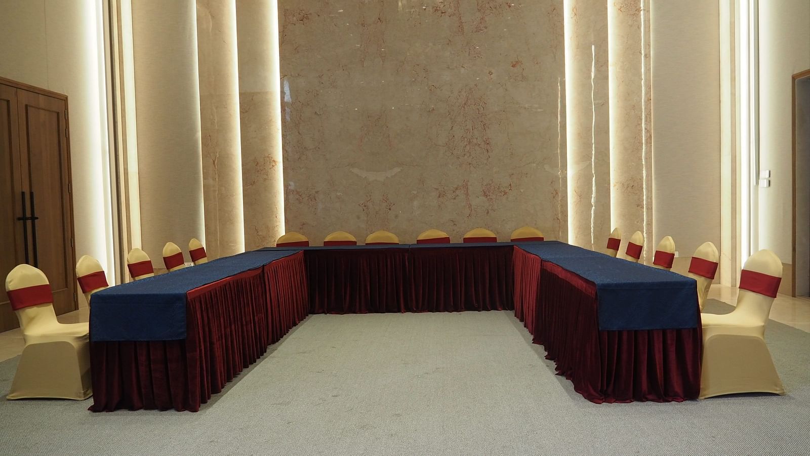 A U-shaped table with blue cloth and chairs in a grand, symmetrical hall - Club Charholi, Pune 