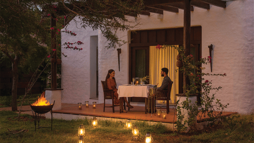 A couple having a romantic dinner in Bandipur with lights next to them at The Serai Bandipur.